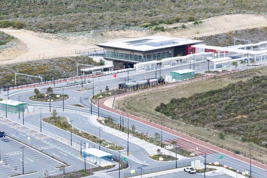 Aerial view of a modern train station with a bus interchange, parking facilities, and surrounding native vegetation in Perth, Western Australia, Australia.