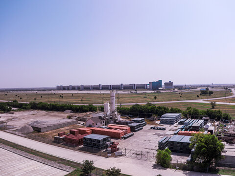 Aerial view of the Texas Motor Speedway in the background with a construction site featuring stacks of bricks and metal materials in the foreground in Fort Worth, Texas, United States.
