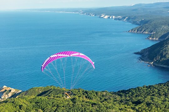 Aerial view of a paramotor flying over the lush green forests and rugged coastline of Cilingoz in Catalca, Istanbul, Turkey.