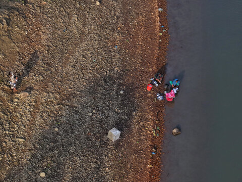 Aerial view of people washing items on the rocky riverbank of the Surma River in Sylhet, Sylhet Division, Bangladesh.