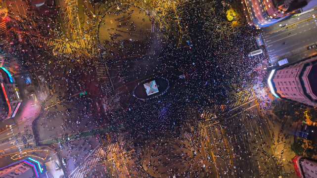 Buenos Aires, CABA, Argentina - 19 July 2026: Aerial view of a massive crowd gathered around the Obelisco at night, with illuminated city streets and urban architecture.