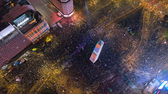 Buenos Aires, Argentina - 19 July 2026: Aerial view of the Obelisco surrounded by a massive crowd celebrating on Avenida 9 de Julio under night city lights.