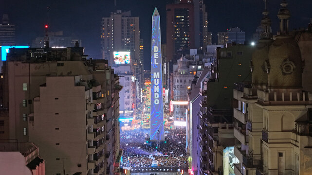 Buenos Aires, CABA, Argentina - 19 July 2026: Aerial view of the illuminated Obelisco de Buenos Aires surrounded by a massive crowd celebrating on Avenida 9 de Julio at night.