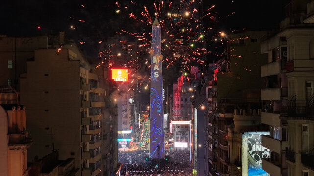 Buenos Aires, Argentina - 19 July 2026: Aerial view of the Obelisco de Buenos Aires illuminated at night during a vibrant public celebration with fireworks bursting above the city skyline.