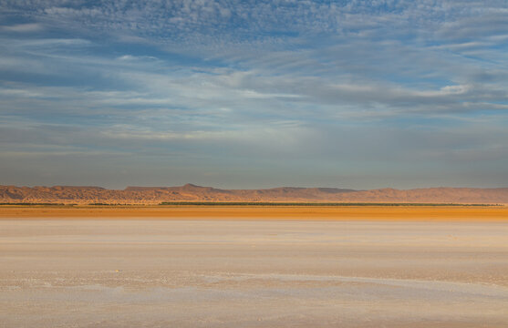 View of the vast salt flats of Chott el Djerid with distant mountains under a cloudy sky in Tozeur, Tozeur Governorate, Tunisia.