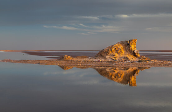 View of salt formations at Chott el Djerid reflecting in shallow water under a dramatic sunset sky in Tozeur, Tozeur Governorate, Tunisia.