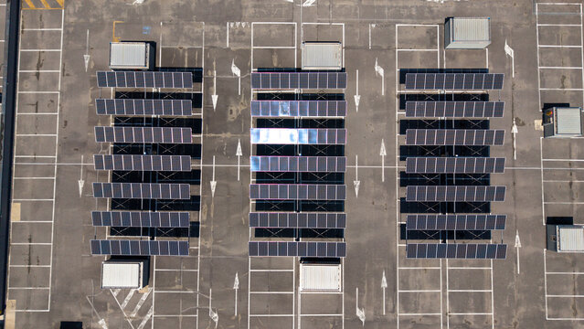 Aerial view of a commercial retail complex featuring rows of photovoltaic panels installed on the roof, showcasing sustainable energy infrastructure in Peschiera Borromeo, Lombardy, Italy.