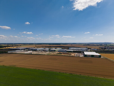 Aerial view of the industrial area near Gross Munzel with large warehouses surrounded by agricultural fields under a clear blue sky in Barsinghausen, Lower Saxony, Germany.