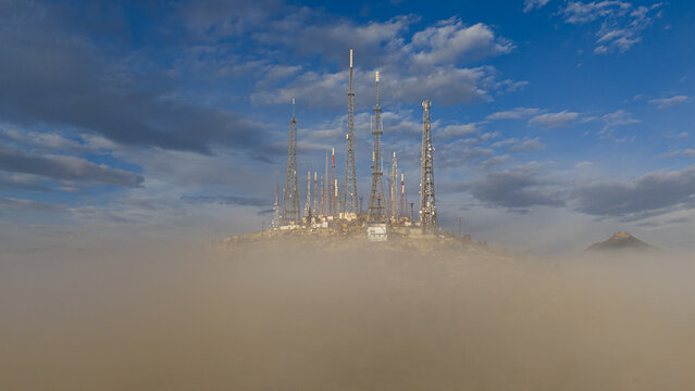 Aerial view of Akyokus radio and television towers rising above a thick layer of morning fog under a blue sky in Meram, Konya, Turkiye.