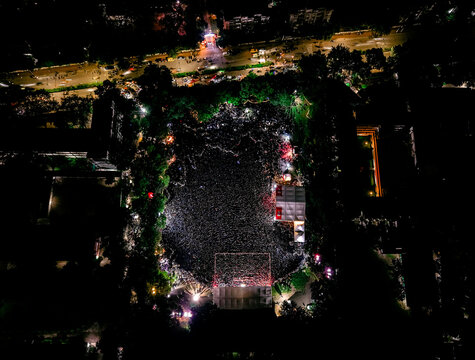 Dhaka, Bangladesh - 20 July 2026: Aerial view of a massive crowd gathered in a park at night, illuminated by stage lights and surrounded by dark trees and city streets.