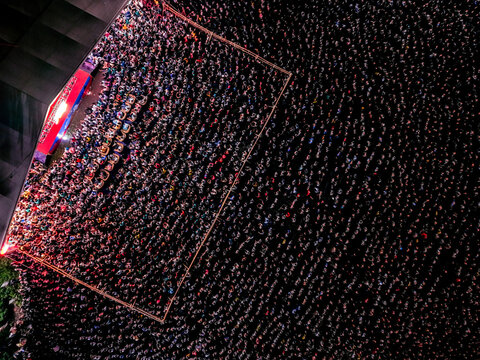Dhaka, Bangladesh - 20 July 2026: Aerial view of a massive crowd gathered at night for a public event, with the illuminated stage area casting light over the dense assembly of people.