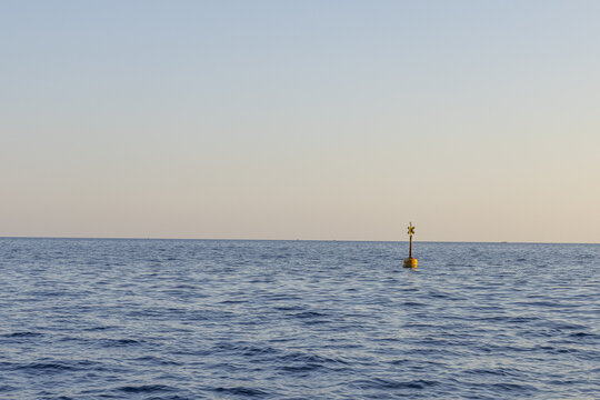 View of a yellow navigation buoy floating in the calm blue waters of the Ligurian Sea in Monterosso al Mare, Liguria, Italy.