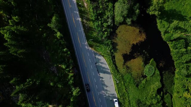 Aerial view of a winding road cutting through dense pine forests in the rural landscape of Morgedal, Telemark, Norway.