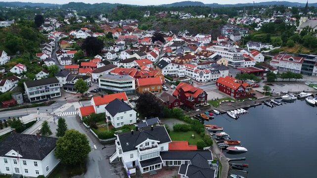 Aerial view of the coastal town of Grimstad with colorful houses, a harbor with boats, and lush greenery in Grimstad, Agder, Norway.