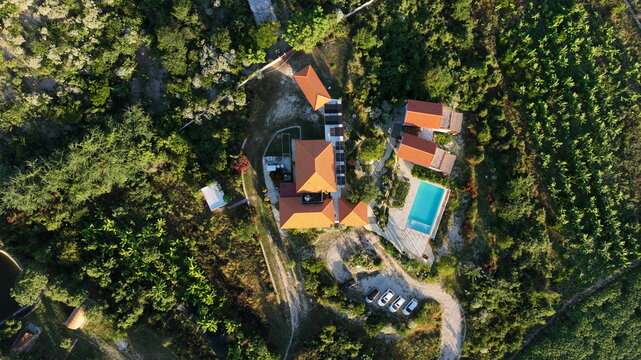 Aerial view of Altos de La Caobita Eco-hotel featuring terracotta-roofed buildings, a swimming pool, and surrounding lush vegetation in Barrera, Azua, Dominican Republic.