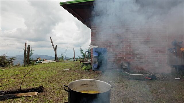 cooking meat on an outdoor grill with smoke near a rustic brick house