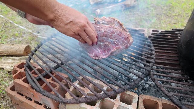 grilling meat on an outdoor brick barbecue pit with a large cooking pot