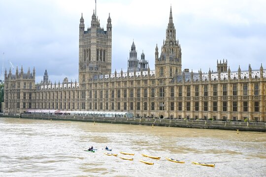View of the Palace of Westminster with people kayaking on the River Thames in London, England, United Kingdom.