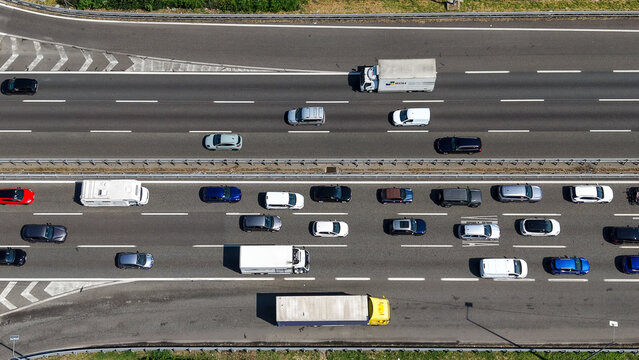 Milan, Lombardy, Italy - 15 July 2026: Aerial view of heavy traffic on a multi-lane highway with various cars and trucks moving along the asphalt road under bright daylight.