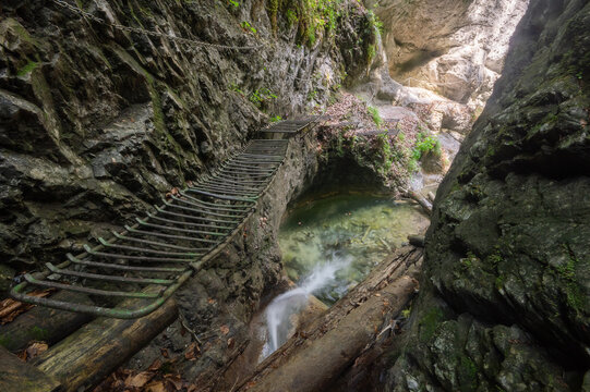 View of the metal ladder bridge over a small waterfall and clear pool within the rocky walls of Roth Gorge in Slovak Paradise National Park, Stratena, Kosice Region, Slovakia.