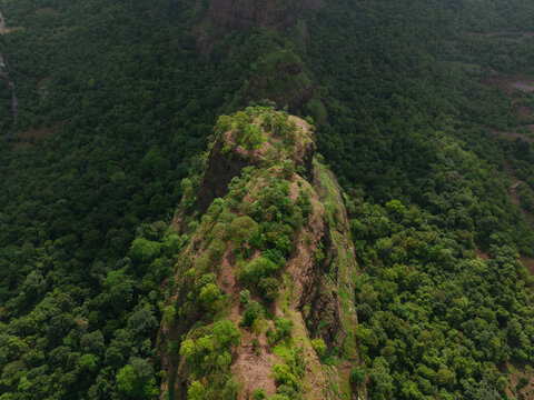 Aerial view of Mrugagad Fort surrounded by dense green forests and rocky terrain in Bheliv, Maharashtra, India.