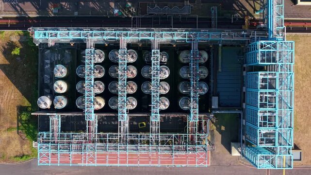 Aerial view of the industrial infrastructure at Humber Innovation Park with rows of storage tanks and complex blue steel piping systems in Grimsby, England, United Kingdom.