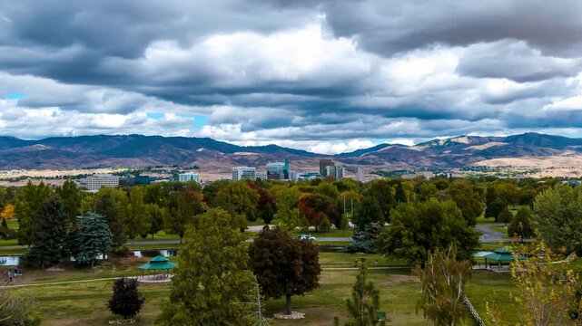Aerial view of Ann Morrison Park with lush greenery and the Boise city skyline set against distant mountains in Boise, Idaho, United States.