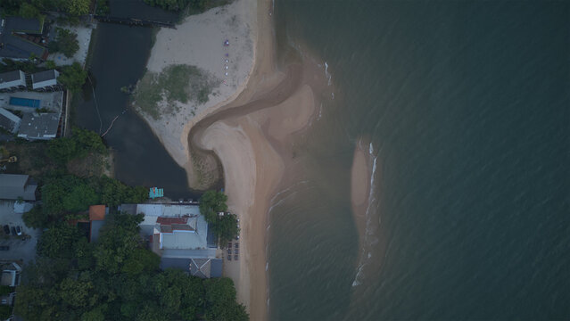 Aerial view of the sandy coastline and calm waters at Ao Nang beach, with lush green trees and resort buildings along the shore in Ao Nang, Krabi, Thailand.