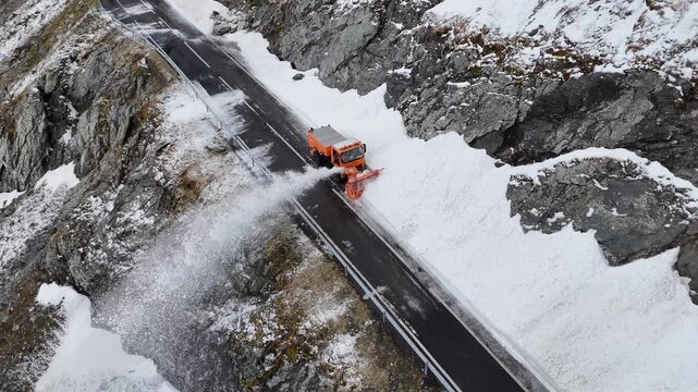 Aerial view of a snowblower truck clearing heavy snow from the winding Transfagarasan mountain road in Curtea de Arges, Judetul Arges, Romania.