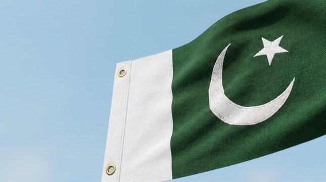 Pakistan flag waves against a clear blue sky in a display of national pride and unity.