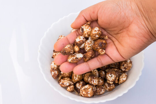 hand  holding jaggery and cocoa-coated makhana, delicious homemade Indian snack prepared from roasted fox nuts