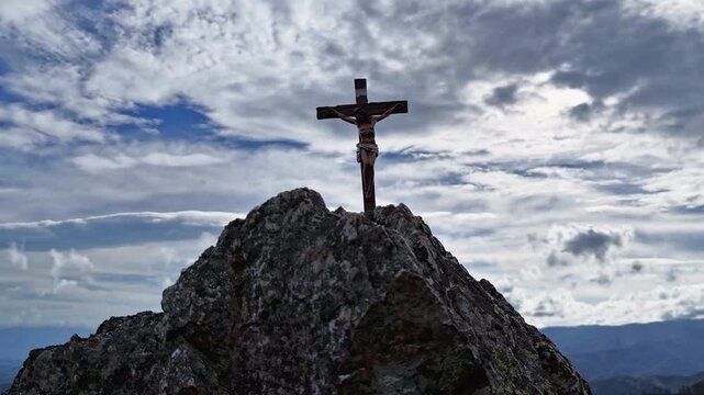 Silhouettes of crucifix symbol on top mountain with bright sunbeam on the colorful sky background	