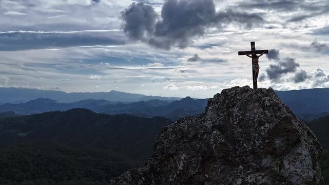 Silhouettes of crucifix symbol on top mountain with bright sunbeam on the colorful sky background	
