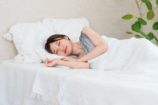 A young Asian woman sleeping in a bed (sleep, restful sleep, sleep duration, good sleep)