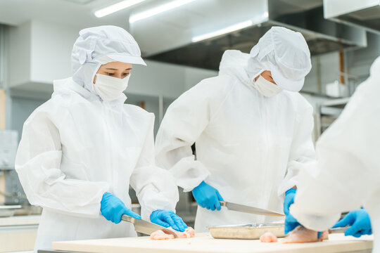 Male and female staff wearing sanitary clothing while working in food processing (food hygiene, food factory, hygiene management)