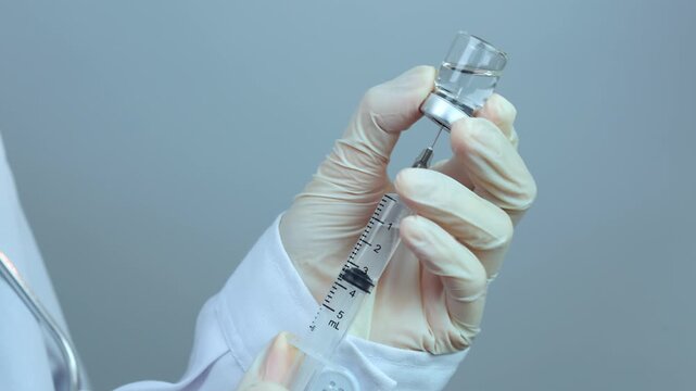 Focused doctor carefully prepares medical syringe injection vial, providing professional weight management treatment and clinical care