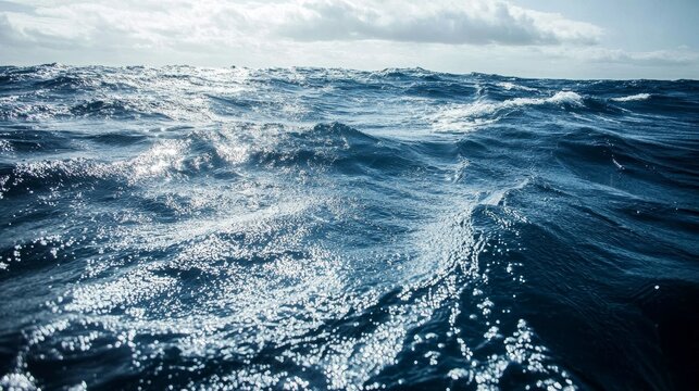 Vast deep ocean landscape during summer with dark blue water and choppy waves under a cloudy sky