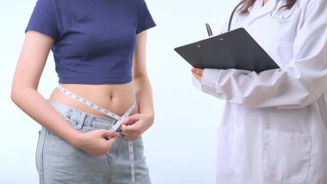 Determined patient and doctor track body measure progress during successful healthy weight loss journey inside modern clinic consultation