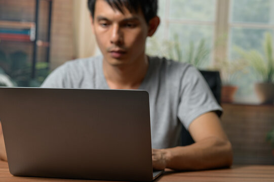 Young Man Working on Laptop at Desk in Modern Home Office Setting