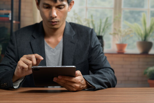 Young Man in Business Attire Using Tablet During Work at Desk