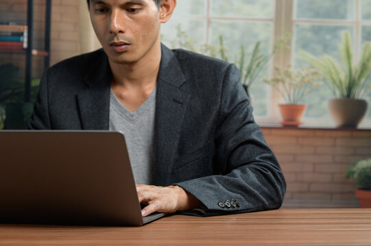 Businessman Working on Laptop at Desk in Modern Office Environment