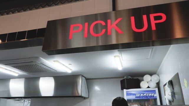 음식점 카운터 상단에 빨간색 글씨로 PICK UP 문구가 적힌 깔끔한 안내 표지판