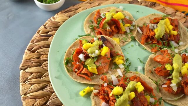 Aerial view of fresh tacos al pastor topped with guacamole sauce and pineapple slices