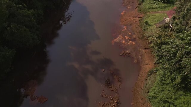Tilt up Aerial view of Khlong Phrasaeng red river bed with reflective water and long suspension rope bridge near Khao Sok National Park in Surat Thani Province, Thailand