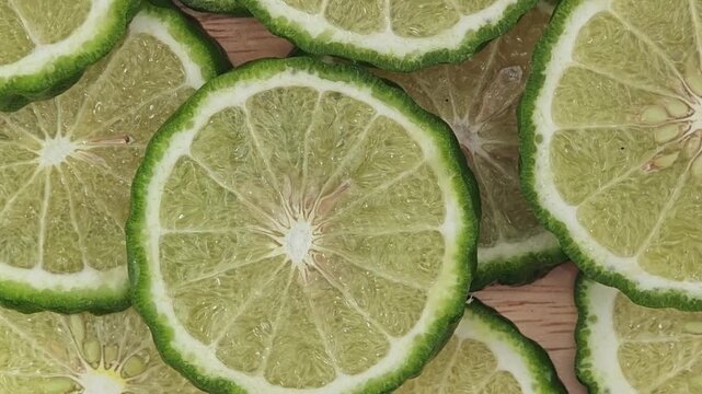Sliced kaffir lime on wooden plate. Rotation.