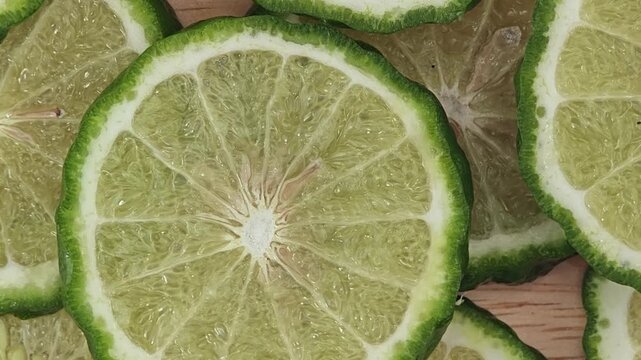 Sliced kaffir lime on wooden plate. Zoom out.