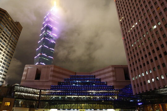Taipei 101 tower glows through fog at night.