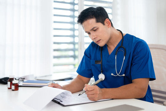 male doctor reviewing patient medical charts at the clinic office.