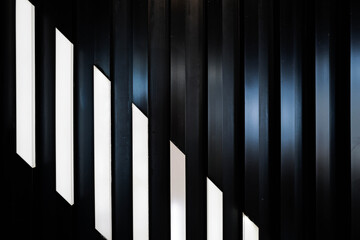 Naklejka premium Abstract black metallic slat wall background with diagonal white geometric pattern. stylish geometric rhythm, dynamic depth, and futuristic luxury aesthetic. Ideal for modern architecture cover
