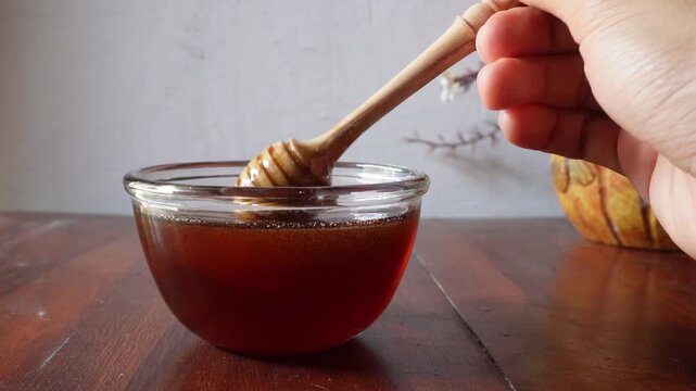Honey dripping in the glass jar from honey dipper 